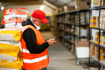 An older worker in a pet food warehouse prepares deliveries of goods for pet stores.Cheerfully does his job.