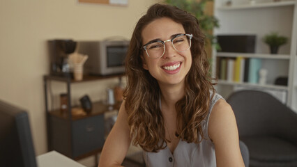 Young hispanic woman types on computer keyboard while looking at monitor in office building;...