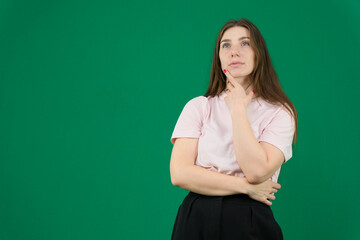 Thoughtful young woman in casual white t-shirt and black pants sitting indoors, posing with hands near face. Minimalistic portrait with natural light and modern lifestyle mood. High quality photo