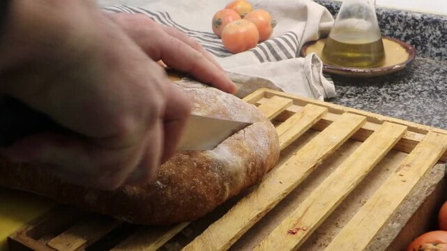 Man cutting a rustic bread with Kalamata Olives made from 2 kilos of flour, homemade