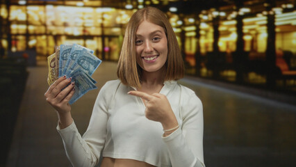 Woman happily holding hungarian forint banknotes on a city street at night, showcasing currency outdoors with excitement and joy, featuring urban background and illuminated scenery.