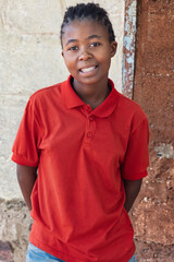 village african young girl teenager, with braids hairstyle , outdoors in the nature, at home , in front of the house wall