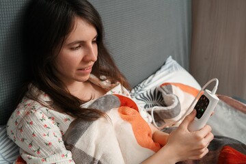 Woman adjusting electric heated blanket in bed