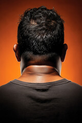 Obraz premium Nuca y pelo corto de hombre con fondo naranja, Imagen para campaña de alopecia masculina, Fondo para contenido sobre salud capilar, Foto con iluminación dramática para editorial de moda