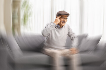 Senior man seated on a sofa feeling dizzy