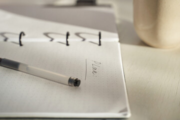 Notebook with handwritten plan and pen on table with coffee representing personal organization and daily routine.