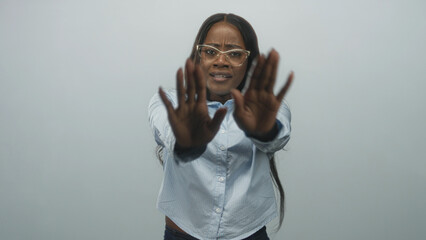 Woman holding palms out with hands raised, eyeglasses and light blue buttoned shirt visible in studio; rejection boundary caution.
