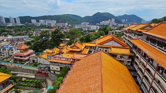 Kek Lok Si Buddhist temple complex on hillside in Penang, Malaysia. Colorful pagodas, shrines and white tower with golden spire surrounded by lush green trees. Traditional Asian architecture under blu