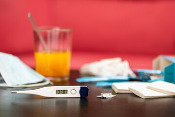 Illness and fever concept with thermometer and medicine at home