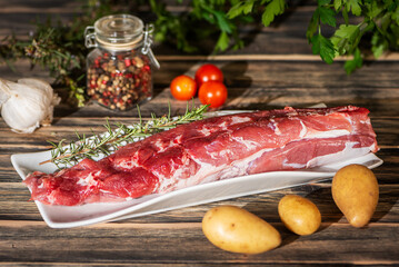 Raw pork tenderloin prepared with vegetables and aromatic herbs, close up