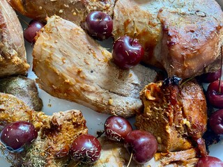 Portions of roasted pork belly and fresh cherries isolated on a plate