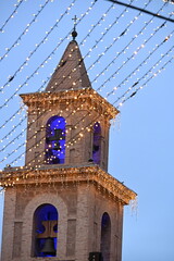 Church facade and tower in Torrevieja decorated with holiday lights
