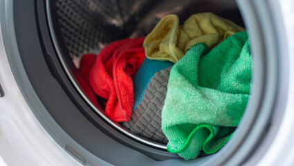 multicolored bright microfiber cloths inside the metal drum of a washing machine