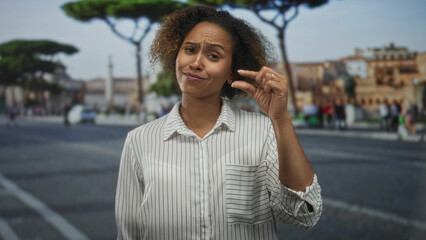 Fototapeta premium Woman smiling, holding small object between fingers and showing hand in striped shirt on street; optimism travel discovery.