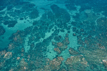 Aerial drone shot of turquoise tropical sea with coral reef patterns and crystal-clear lagoon water&mdash;clean seascape background, natural texture, no people, copy space, top view, 4K, travel.