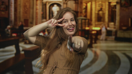 Smiling redhead woman eagerly points finger to camera in ornate historic building among wooden...