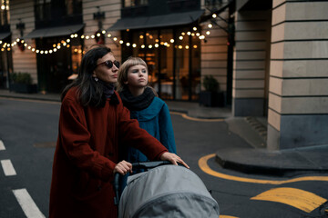 Mother and daughter wearing coats at walk in evening city