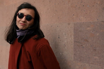 Brunette smiling woman in red coat and sunglasses outside