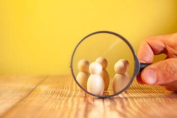 human figure holding magnifying glass in hand on wooden table