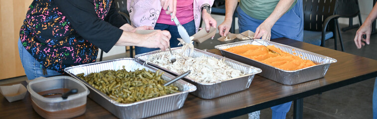 Three women serving thanksgiving food from trays