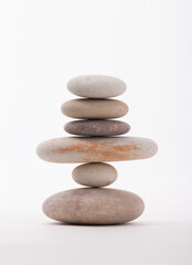 Zen stone stacking showcases balance and mindfulness. A simple arrangement of rocks is isolated on a clean white background, perfect for illustrating concepts like harmony and equilibrium.