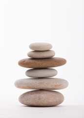 Stack of smooth stones, artfully arranged against a clean white backdrop. This composition evokes a sense of balance, tranquility, and mindfulness.