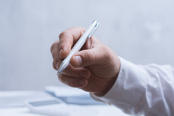 Male hand with pen reviewing printed reports and charts. Professional business, finance, audit and corporate workflow concept with copy space.