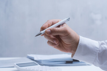 Male hand with pen reviewing printed reports and charts. Professional business, finance, audit and corporate workflow concept with copy space.