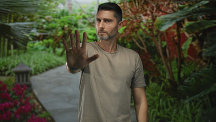 Man with palm forward stop gesture in a forest setting showing outstretched hand and stern expression; personal boundary concern.