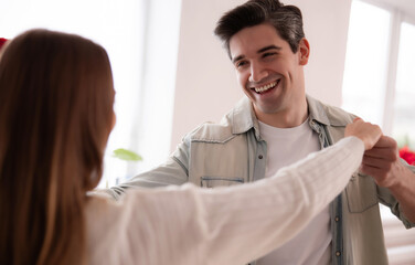 Obraz premium Happy young couple dancing together at home, smiling and enjoying quality time indoors. Romantic lifestyle moment, love, relationship, happiness, casual home interior. 
