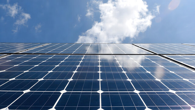 Close-up texture of solar panel photovoltaic cells with bright sun flare reflection, renewable clean energy technology background. - Powered by Adobe