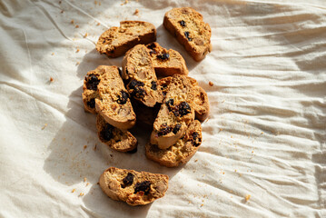Italian cantuccini biscotti with nuts and dried fruits served on a white linen cloth with scattered ingredients