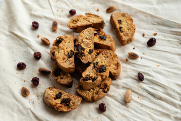 Italian cantuccini biscotti with nuts and dried fruits served on a white linen cloth with scattered ingredients