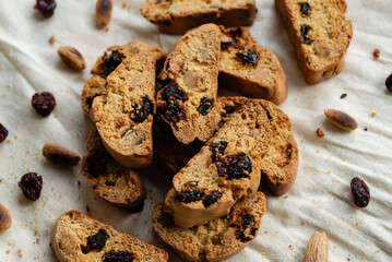 Italian cantuccini biscotti with nuts and dried fruits served on a white linen cloth with scattered ingredients