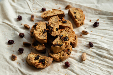 Italian cantuccini biscotti with hazelnuts and cranberries served on a white linen cloth with scattered ingredients