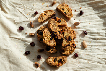 Italian cantuccini biscotti with hazelnuts and cranberries served on a white linen cloth with scattered ingredients