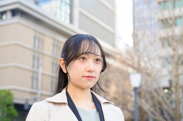スーツを着てビル街に立つ20代フレッシャーズのビジネスウーマン