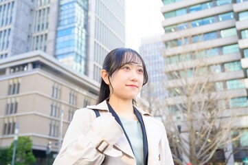 スーツを着てビル街に立つ20代フレッシャーズのビジネスウーマン