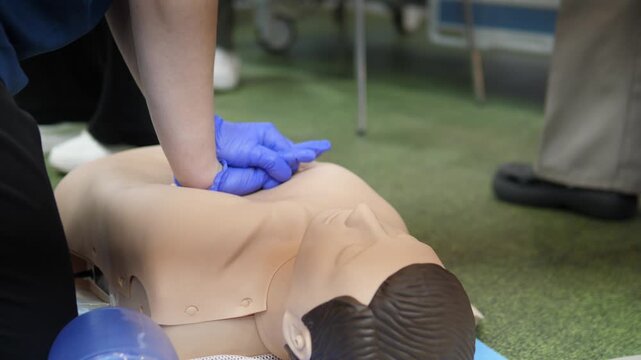 team performing chest compressions with bag valve mask on mannequin in training room combined compression and ventilation practice with blue gloves and supporting staff, realistic