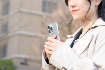 ビル街でスマホを使用する日本人ビジネスウーマン
