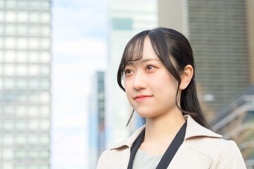 スーツを着てビル街に立つ20代フレッシャーズのビジネスウーマン