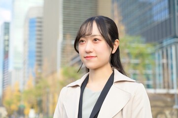 スーツを着てビル街に立つ20代フレッシャーズのビジネスウーマン