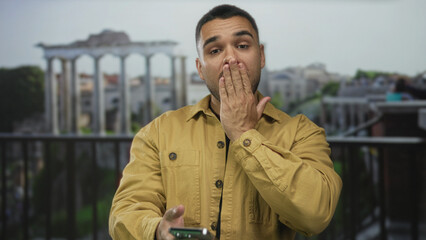 Man covers mouth with hand at ancient roman ruins outdoors by stone columns; surprise introspection...