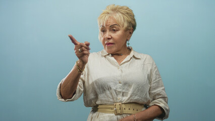 Senior woman pointing finger and touching chin in studio portrait, expressive hand gestures and portrait pose; thoughtful contemplation.