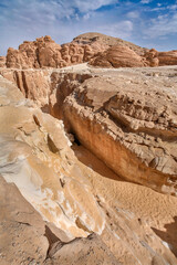 Narrow passage in White Canyon, Wadi Qunai, Sinai Peninsula, Egypt. Sunlit sandstone walls shaped by wind erosion in an arid desert landscape.