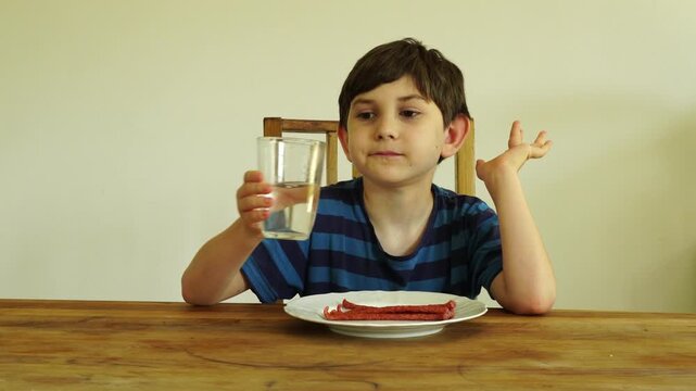 Boy eats dried cabanossi at the table
