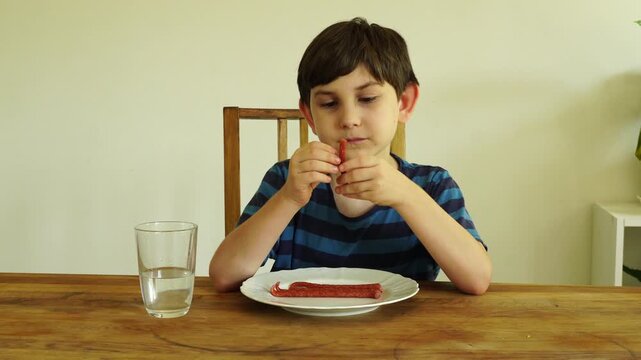 Boy eats dried cabanossi at the table
