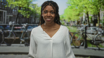 Woman smiling with eyes closed on an amsterdam street canal beside parked bicycles and iron railing; contemplation.