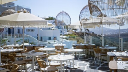 Sunny seaside terrace with wicker tables, umbrellas and hanging rattan lights, soft blurred shallow bokeh cafe; background backdrop overlay calm.
