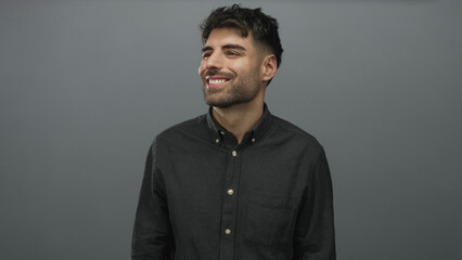 Obraz premium Man wearing casual buttondown shirt looking up and smiling against grey studio wall; optimism growth ambition.
